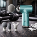 Turquoise massage gun with attachments on a dark surface