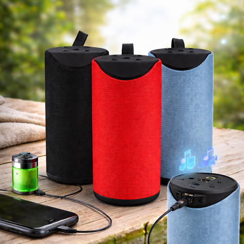 Three cylindrical speakers in black, red, and blue on a wooden surface with a blurred natural background.