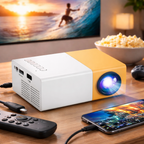 Yellow and white projector on a table with a phone, remote, and bowl of popcorn.